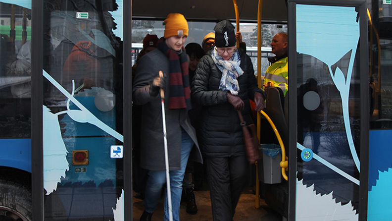 A traveler getting off av bus with the help of a fellow traveler